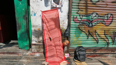 Un niño sin hogar estudia fuera de una tienda cerrada en una calle en Calcuta. REUTERS/Rupak De Chowdhuri