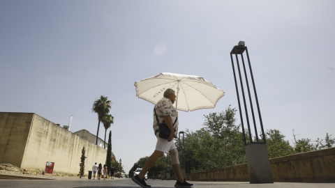 Un hombre se protege del sol con una sombrilla en una jornada de intenso calor. Un hombre se protege del sol con una sombrilla en una jornada de intenso calor.