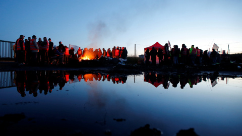 Trabajadores franceses y manifestantes junto a una barricada en llamas para bloquear la entrada del depósito de la sociedad SFDM cerca de la refinería de petróleo de Donges. REUTERS/Stephane Mahe