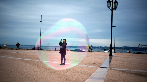 Un turista, a través de una burbuja de jabón mientras se toma una foto en la plaza de Comercio, en el centro de Lisboa. // RAFAEL MARCHANTE (REUTERS)