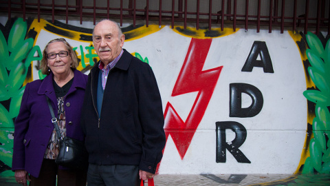 Natividad y Eladio, dos vecinos de Vallecas y afionados del club, posan ante una pintada con el escudo del club. // CHRISTIAN GONZÁLEZ