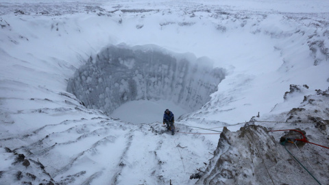 Un miembro de una expedición, en el borde de un cráter recién formado en la península de Yamal, en el norte de Siberia. // VLADIMIR PUSHKAREV (REUTERS)