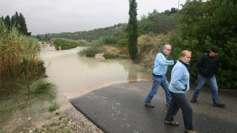 Varias personas junto a una carretera cortada en Tortosa a causa del temporal que desde ayer azota Cataluña que ha obligado a cortar al tráfico numerosas carreteras. // EFE