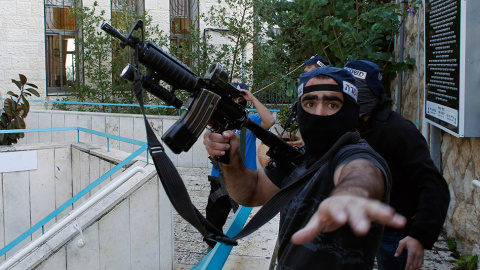 Un policía israelí gesticula mientras sostiene un arma cerca de la escena de un ataque a una sinagoga en Jerusalén. // RONEN ZVULUN (REUTERS)