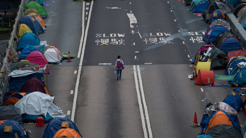 Una mujer camina en un paso elevado en el lugar en el que acampan los manifestantes por la democracia en el distrito Almirantazgo de Hong Kong. // JOHANNES EISELE (AFP)