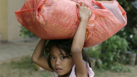 Una niña filipina cargada con sus pertenencias, camina hacia el centro de refugiados en Manila. // EFE/EPA/DENNIS M. SABANGAN