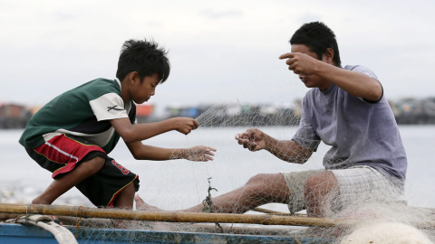 Un padre y su hijo aseguran su barca de pesca para prevernir la llegada del tifón Hagupit. // EFE/EPA/DENNIS M. SABANGAN