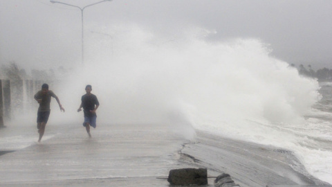 Un par de personas corren para evitar las olas provocadas por el tfón Hagupit, en la ciudad de Legazpi, en la provincia filipina de Albay. // EFE/EPA/ZALRIAN Z. SAYAT