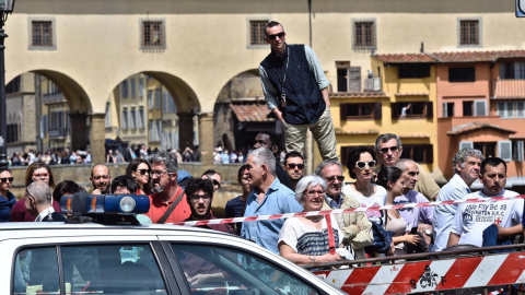 Varios curiosos congregados para ver las labores de rescate de los vehículos engullidos por un socavón cerca del famoso Puente Viejo a orillas del río Arno, en el centro de la ciudad italiana de Florencia (Italia). EFE/Maurizio Degl' Innoce