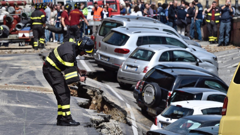 Un bombero trabaja en el rescate de varios vehículos engullidos por un socavón cerca del famoso Puente Viejo a orillas del río Arno, en el centro de la ciudad italiana de Florencia (Italia). EFE/Maurizio Degl' Innocenti