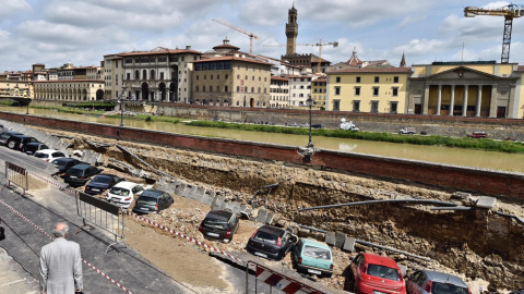 Un viandante observa los vehículos engullidos por un socavón cerca del famoso Puente Viejo a orillas del río Arno, en el centro de la ciudad italiana de Florencia (Italia). EFE/Maurizio Degl' Innocenti