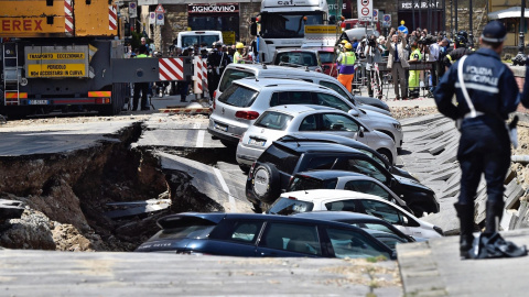 Los servicios de emergencia trabajan en la retirada de los vehículos engullidos por un socavón cerca del famoso Puente Viejo a orillas del río Arno, en el centro de la ciudad italiana de Florencia. EFE/Maurizio Degl' Innocenti