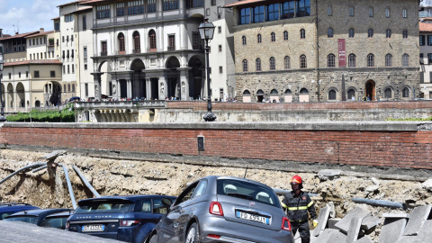 Los servicios de emergencia trabajan en la retirada de los vehículos engullidos por un socavón cerca del famoso Puente Viejo a orillas del río Arno, en el centro de la ciudad italiana de Florencia. EFE/Maurizio Degl' Innocenti
