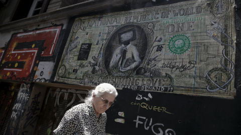 Una mujer pasa por delante de una pintada en Atenas que caricaturiza un billete de dólar. REUTERS/Alkis Konstantinidis Una mujer pasa por delante de una pintada en Atenas que caricaturiza un billete de dólar. REUTERS/Alkis Konstantinidis