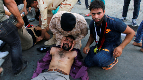 Manifestantes afectados por  gas lacrimógeno en el suelo después de que tratasen de de acercarse a la Zona Verde fortificada en la plaza Tahrir de Bagdad , Irak.- REUTERS / Jalid al Mousily