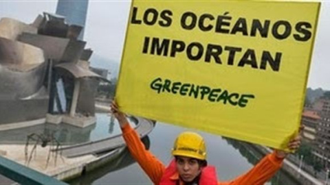 Un activista de Greenpeace, con una pancarta frente al Guggenheim de Bilbao. PEDRO ARMESTRE