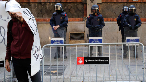 Un manifestante se cubre la cara con una pancarta delante de los policías que vigilaban un edificio del Gobierno, durante una protesta contra la nueva ley de seguridad ciudadana en Barcelona. - REUTERS/Gustau Nacarino