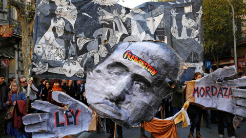 Los manifestantes sostienen una pancarta con el Guernika de Picaso y una caricatura de Franco durante una protesta contra la nueva ley de seguridad ciudadana en Barcelona. - REUTERS