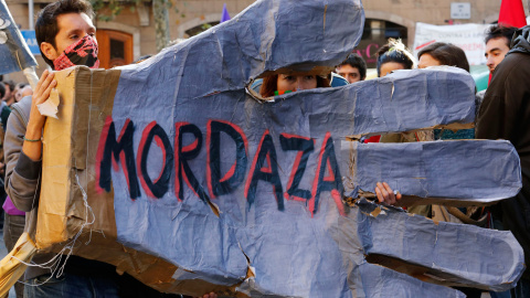 Los manifestantes sostienen un signo de lectura "mordaza" durante una protesta contra la nueva ley de seguridad anti-protesta del gobierno español en Barcelona. -REUTERS