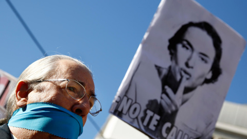 Un hombre, con la boca amordazada, se encuentra bajo un cartel que dice "No te calles" durante una protesta contra la nueva ley de seguridad ciudadana en Madrid. REUTERS