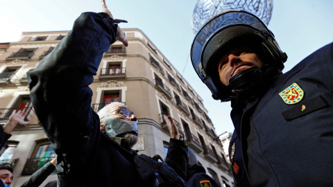 Un hombre, con la boca tapada, se enfrenta con un policía antidisturbios durante una protesta contra la nueva ley de seguridad anti-protesta del gobierno español en Madrid. -REUTERS