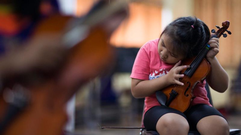 Una estudiante invidente, de 10 años, afina el violín durante un ensayo de la banda en la Escuela para Invidentes e Invidentes con Multiminusvalías en la provincia de Lopburi, Tailandia. EFE/Rungroj Yongrit