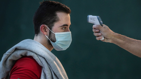 Fotografía de archivo de la toma de temperatura a un joven.
