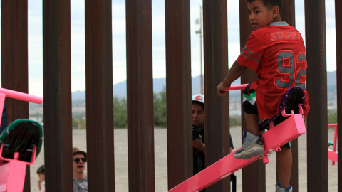 Un joven mexicano, en lo más alto del balancín, mientras un adulto empuja desde la parte norteamericana de la frontera. LUIS TORRES (AFP).