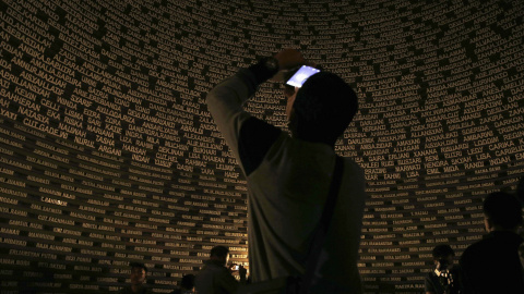 Un visitante toma una fotografía dentro del monumento en Banda Aceh que recoge los nombres de las víctimas del tsunami de 2004.  REUTERS/Beawiharta