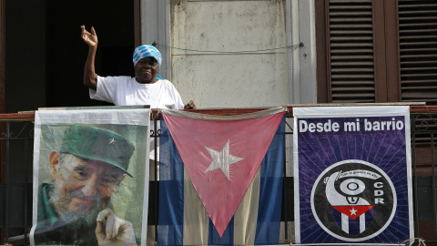 Una saluda desde el balcón de su vivienda adornado con una bandera cubana y la imagen del líder cubano Fidel Castro, en La Habana (Cuba). EFE/Alejandro Ernesto