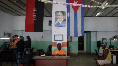 Varios hombres esperan dentro de un taller de reparaciones de televisores en La Habana. EFE/Ernesto Mastrascusa