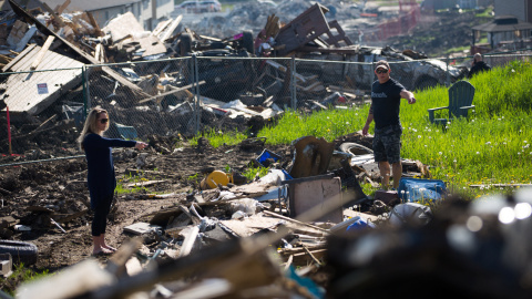 Residentes miran los daños causados por un fuego al vecindario de Timberlea que ha provocado que miles de personas hayan sido evacuadas en Fort McMurray, Alberta, Canadá. REUTERS/Topher Seguin