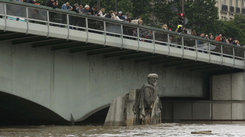 Algunas persoas observan cómo la crecida del Sena cubre la estatua de Zouave en el Puente del Alma, en París. REUTERS/Pascal Rossignol