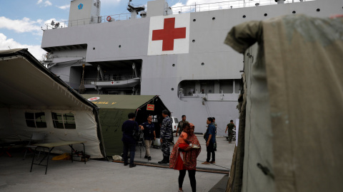 Una mujer sostiene a su hijo mientras espera tratamiento en el barco del hospital de la Armada de Indonesia. REUTERS Una mujer sostiene a su hijo mientras espera tratamiento en el barco del hospital de la Armada de Indonesia. REUTERS