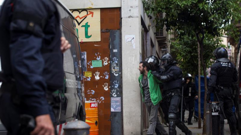 Mossos d'Esquadra custodian a uno de los okupas detenidos por volver a entrar en el edificio que llaman "Banc Expropiat" del barrio barcelonés de Gràcia. EFE/Quique García Mossos d'Esquadra custodian a uno de los okupas detenidos por volver a entrar en el edificio que llaman "Banc Expropiat" del barrio barcelonés de Gràcia. EFE/Quique García