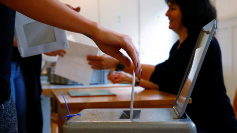 Un cudadano suizo deposita su voto en el referendum sobre el establecimiento de una renta básica mensual. REUTERS/Ruben Sprich