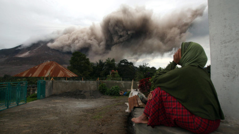 Una mujer observa mientras el Monte Sinabung lanza cenizas piroclásticas hoy, martes 16 de junio de 2015, desde la villa Kuta Tengah, en Karo, al norte de Sumatra./ EFE/Dedi Sahputra