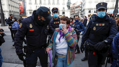 Agentes de la policía socorren a una mujer herida durante la concentración convocada por el Sindicato de Estudiantes y la asociación Libres y Combativas, por el Día de la Mujer hoy lunes en la Puerta del Sol de Madrid.