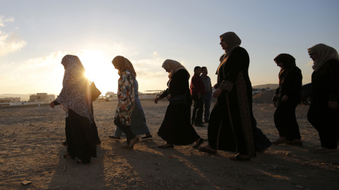 Mujeres palestinas caminan al amanecer hacia el puesto de control de Qalandia, un punto entre la ciudad cisjordana de Ramala y Jerusalén, tras el anuncio del primer ministro israelí, Benjamin Netanyahu, de una serie de medidas de castigo y 