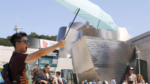 Un turista se protege del sol ante el museo Guggenheim de Bilbao, uno de los destinos demandados en vacaciones. /EFE Un turista se protege del sol ante el museo Guggenheim de Bilbao, uno de los destinos demandados en vacaciones. /EFE