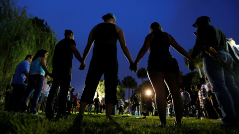 Asistentes a la vigilia en repulsa a la masacre de Orlando forman un círculo uniendo sus manos.- REUTERS