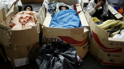 Un sintecho come junto a otros que duermen en la calle en una fría noche en Sao Paulo, Brasil.  REUTERS/Nacho Doce
