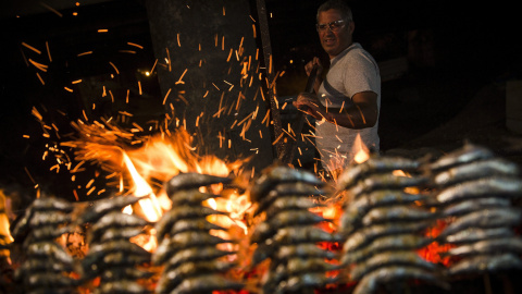 Un hombre prepara unos espetos junto a una hoguera durante las celebraciones de la noche de San Juan en la playa del Rincón de la Victoria, en Málaga. EFE/Jorge Zapata
