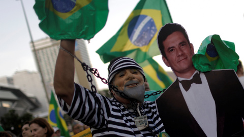 Un hombre disfrazado de preso y una careta de Lula posa con una imagen del polémico juez Sérgio Moro, visto como un héroe entre los antipetistas. - REUTERS