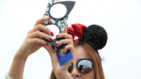 Una chica saca fotos durante la ceremonia de inauguración con unas orejas de Mickey, el producto más deseado