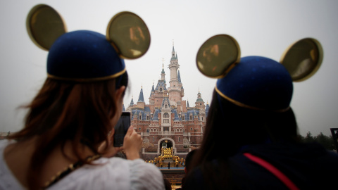 Dos chicas con un gorro de Mickey Mouse haciendo fotos de la gala de inauguración del parque temático