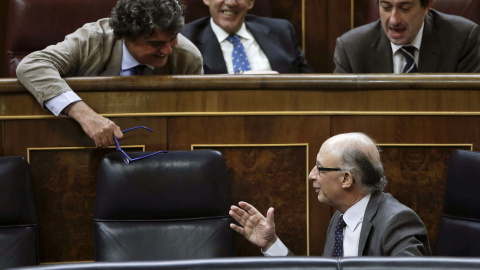 El ministro de Hacienda, Cristóbal Montoro, conversa con Jorge Moragas, en su escaño de diputado. EFE/Emilio Naranjo