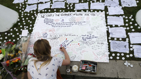Una chica escribe un mensaje de apoyo en una placa en la plaza del Parlamento, en Londres