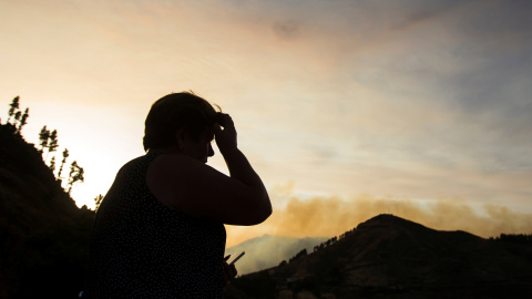 17/08/2019 - Una mujer evacuada de su casa mira el incendio forestal visto en el pueblo de Valleseco, el 1 de agosto / REUTERS - Borja Suárez