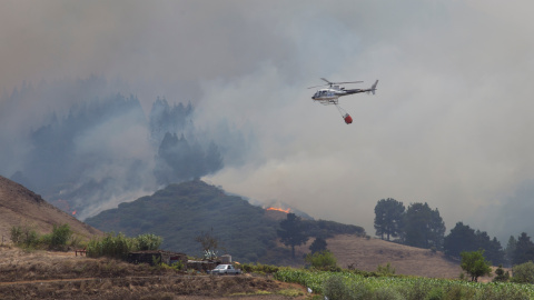18/08/2019 - Un helicóptero transporta agua para combatir el incendio forestal visto en el pueblo de Galdar en la isla canaria de Gran Canaria / REUTERS - Borja Suárez